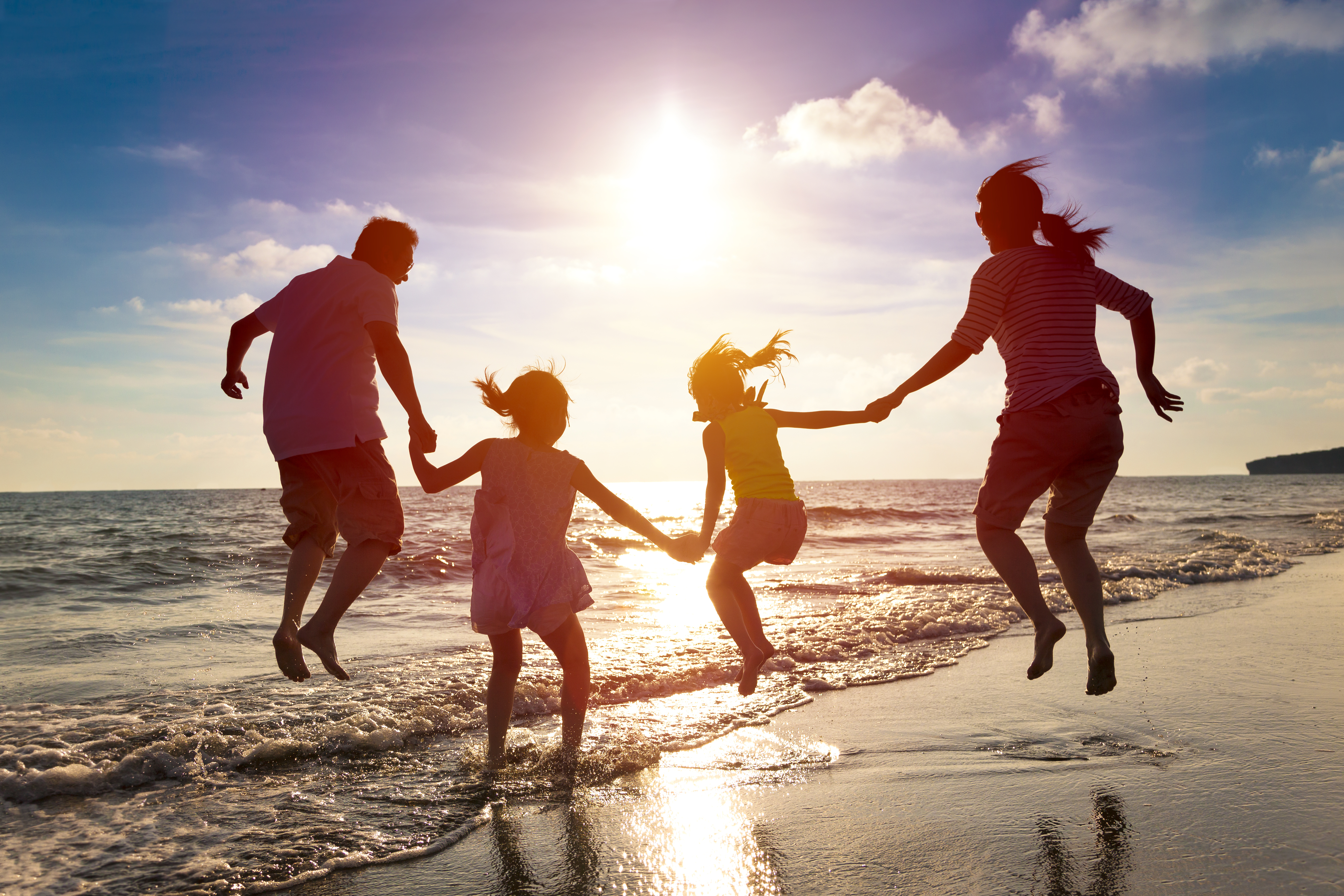 Happy family jumping together on the beach